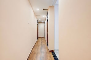Un pasillo con piso de madera, paredes blancas e iluminación empotrada en el techo.