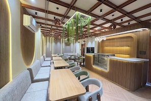 A restaurant interior with wooden beams, hanging plants, and a counter with a wooden finish. - Hotel O J K Galaxy Hotel (Kanpur)