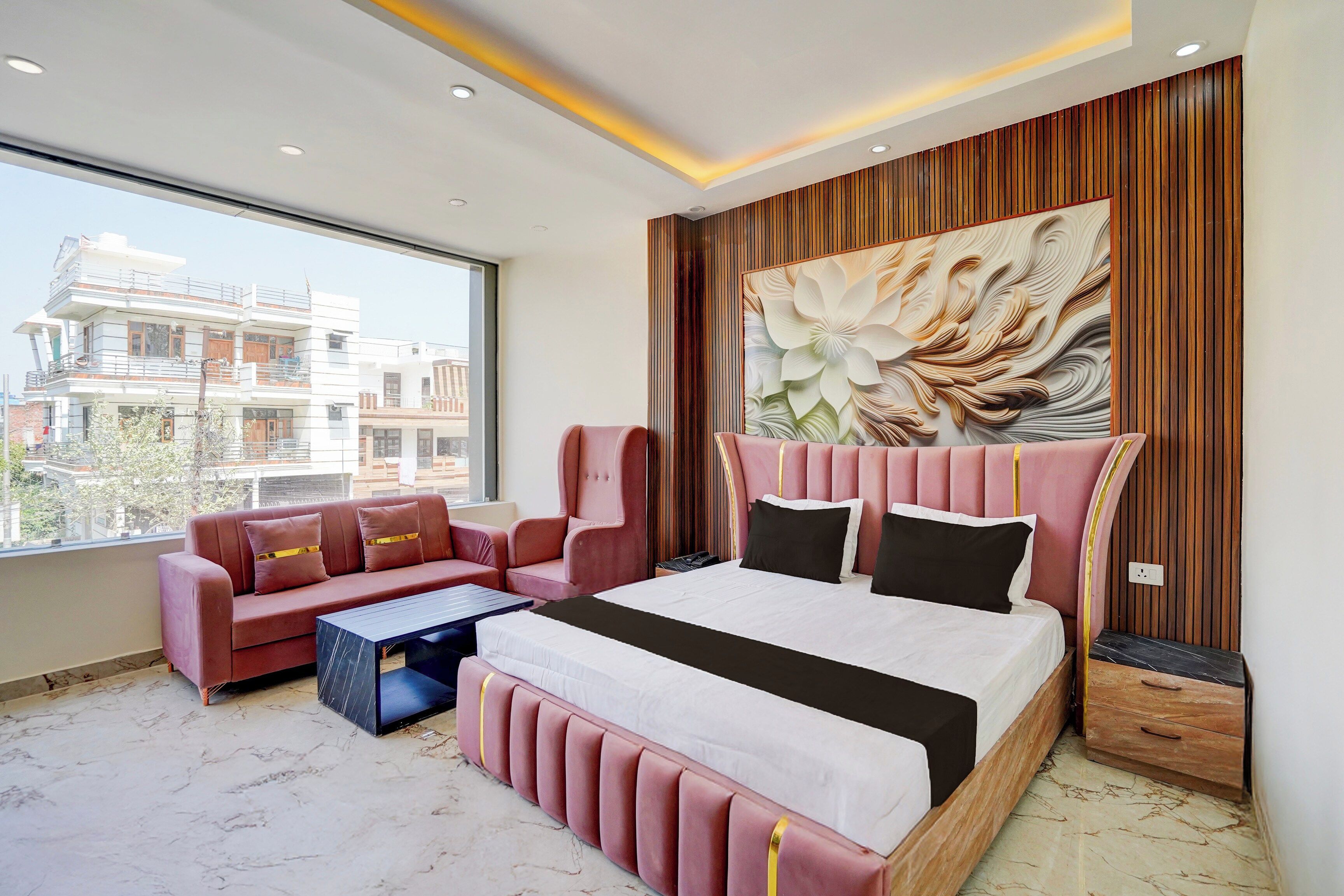Un dormitorio moderno con una cama grande, un sofá y vistas a edificios.