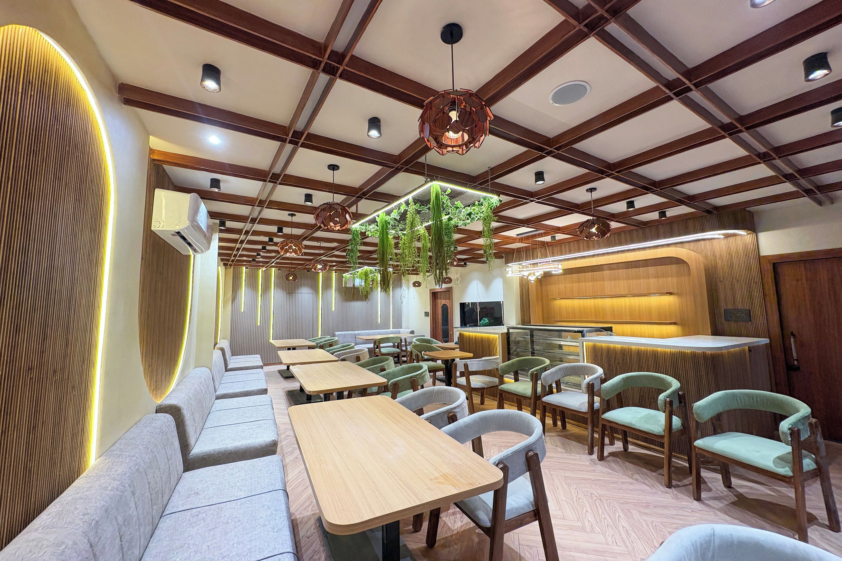 Interior de un restaurante con vigas de madera, plantas colgantes y una zona de bar.