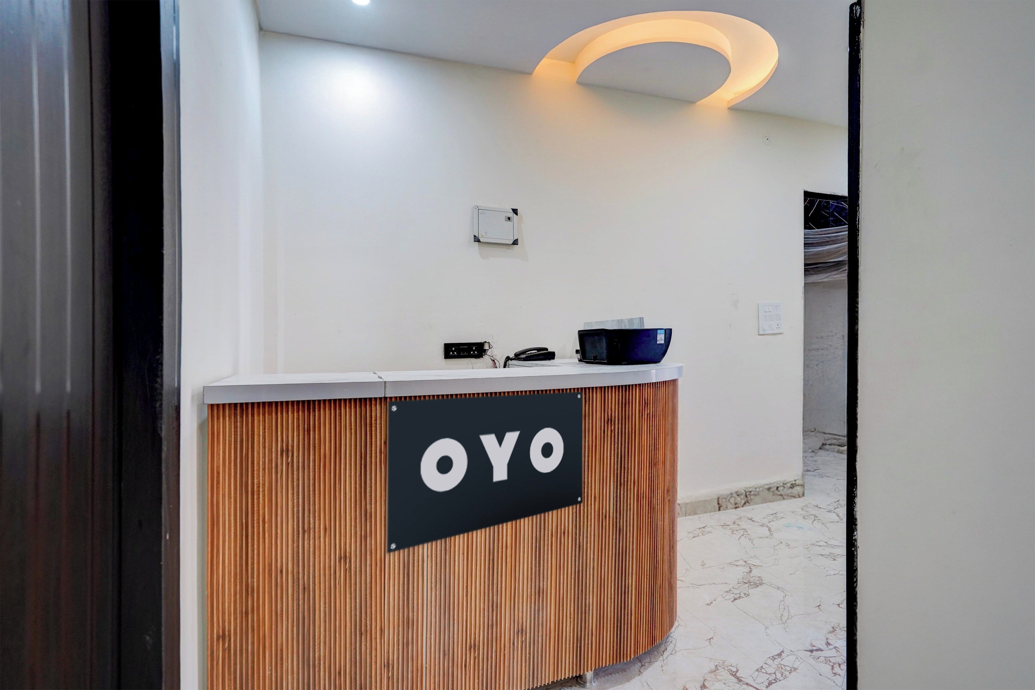 Un mostrador de recepción con un cartel que dice 'OYO' y una lámpara moderna y curvada arriba.