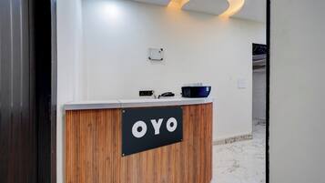 Un mostrador de recepción con un cartel que dice 'OYO' y una lámpara moderna y curvada arriba.