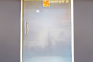 Uma janela com persianas verticais, um puxador e um pequeno objeto decorativo nas persianas.