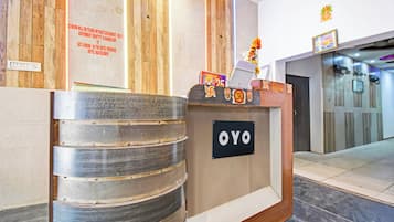 A hotel reception desk with a sign reading 'OYO' and a notice on the wall above it.