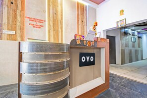 Un comptoir d'accueil d'hôtel avec une enseigne indiquant « OYO » et un avis affiché sur le mur au-dessus.