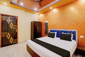 A bedroom with a bed, a wardrobe, and a ceiling fan. - Hotel O Raj In (Kanpur)