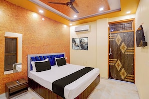 A hotel room with a bed, a nightstand, a wardrobe, and a ceiling fan. - Hotel O Raj In (Kanpur)