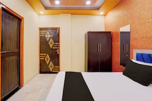 A bedroom with a bed, a wardrobe, and a door. - Hotel O Raj In (Kanpur)