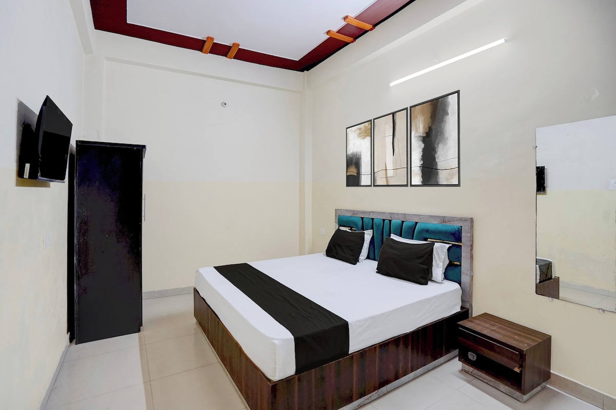 Un dormitorio con cama, televisión, obras de arte y un espejo.