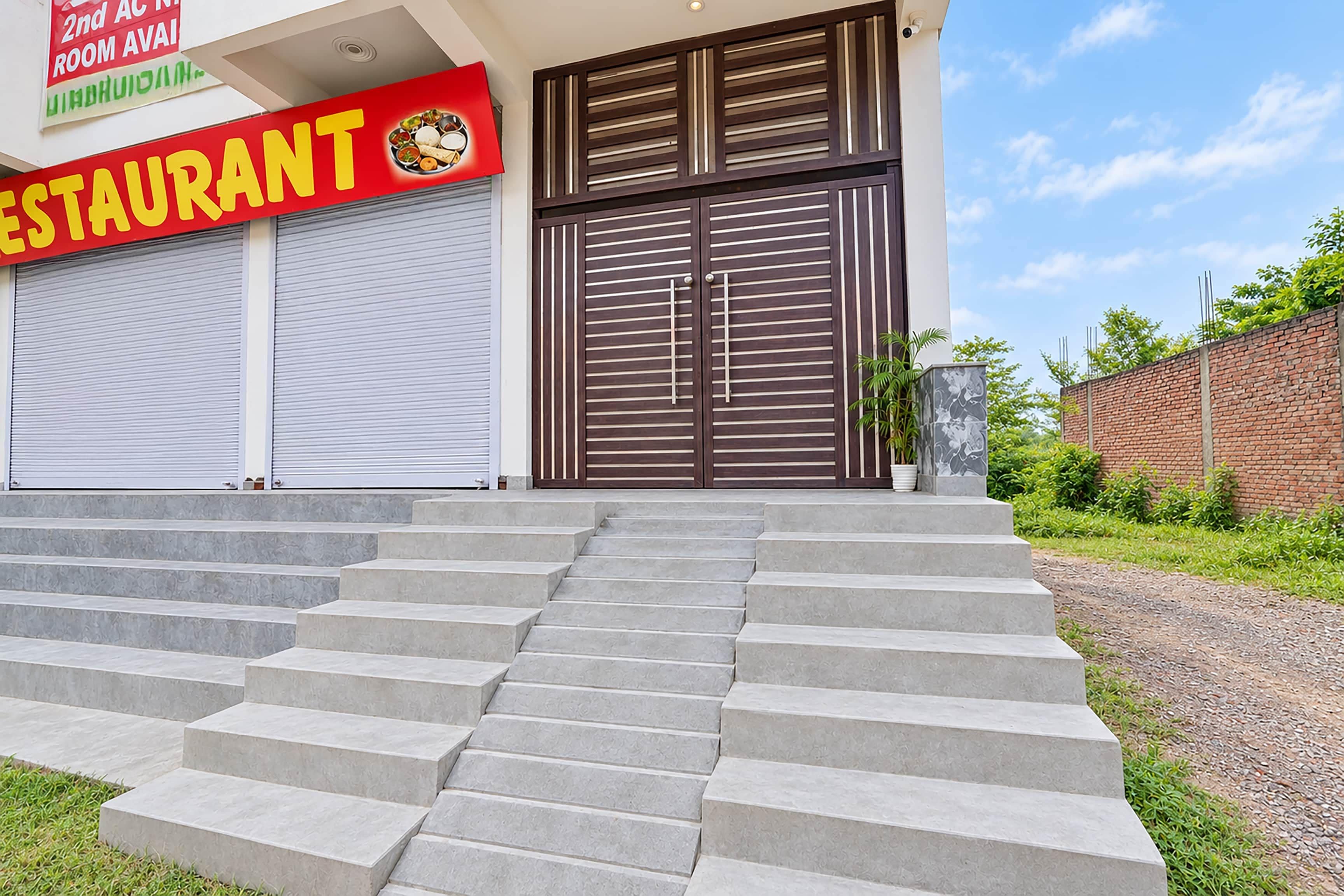 Un restaurante con un letrero rojo, un toldo cerrado y un conjunto de escalones de hormigón que llevan a la entrada.