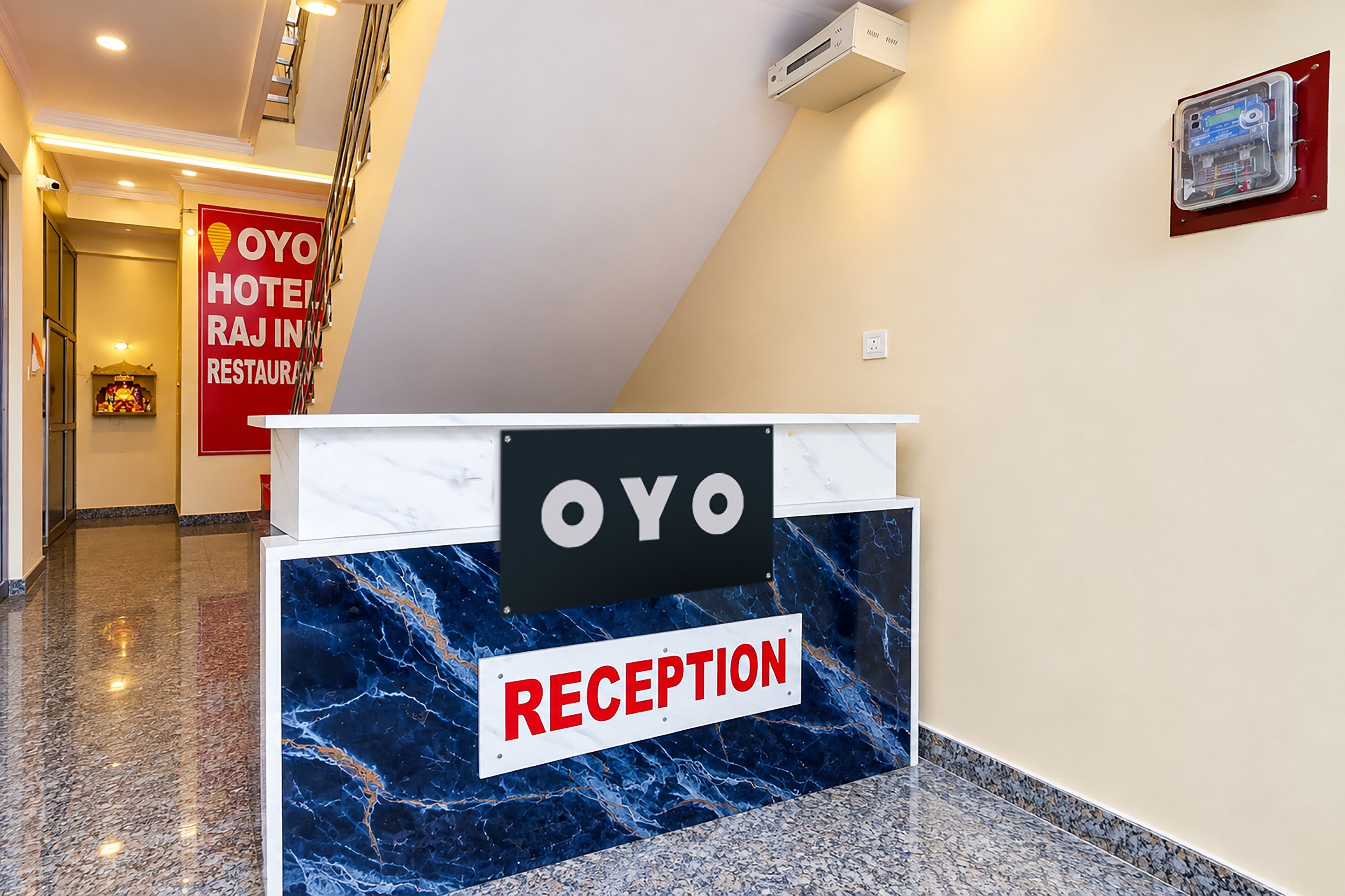 A reception desk with a marble counter and a sign indicating 'OYO HOTEL RAJ INN RESTAURANT'.
