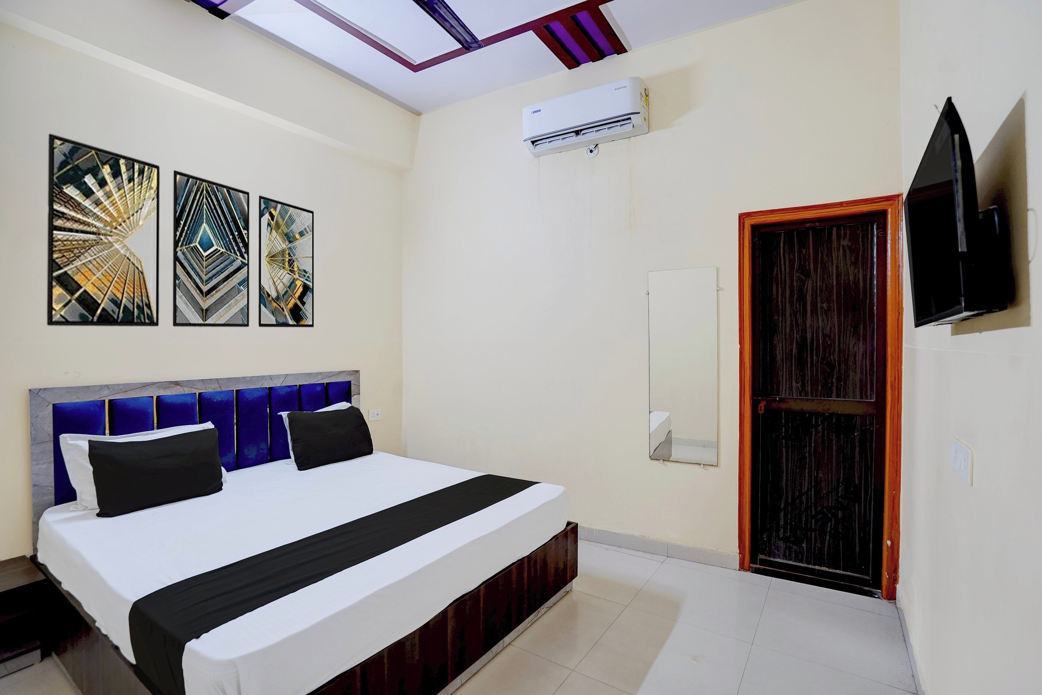 Een hotelkamer met een bed, kunst aan de muur, een airconditioning en een televisie.