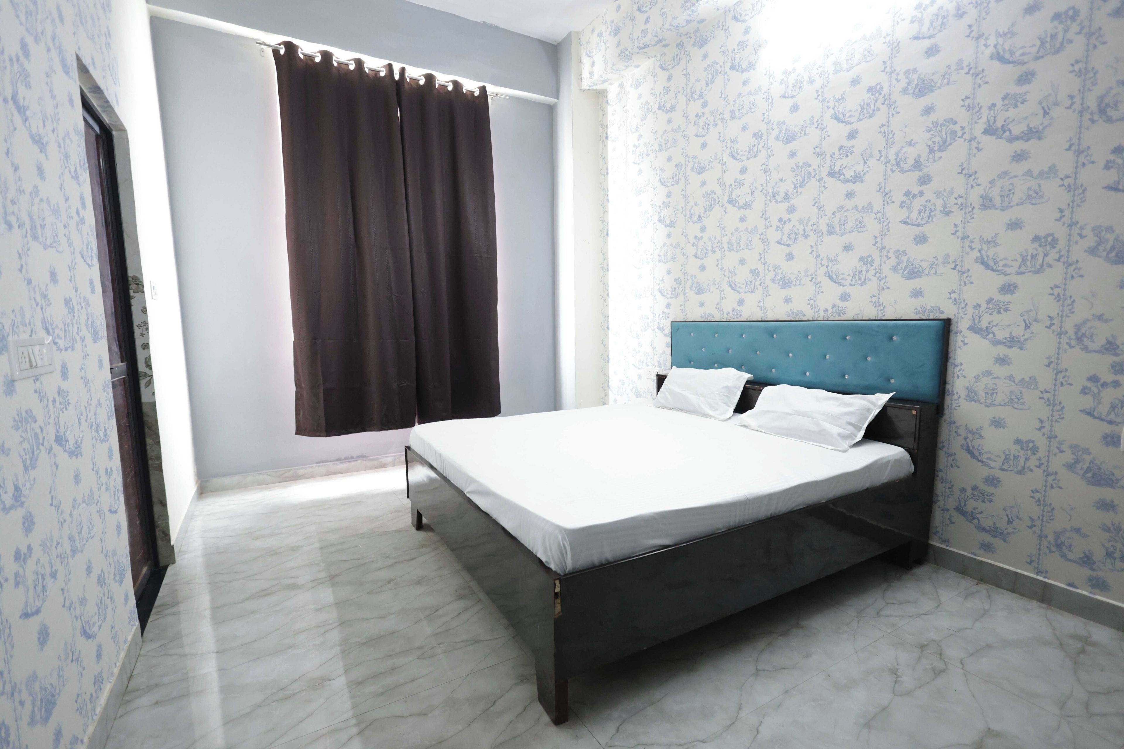 A single bed with a headboard, white bedding, and a window with brown curtains.