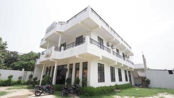 A two-story building with a balcony, a motorcycle parked in front, and a clear sky.