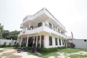 A two-story building with a balcony, a motorcycle parked in front, and a clear sky. - Hotel O Meadows (Mandhana)