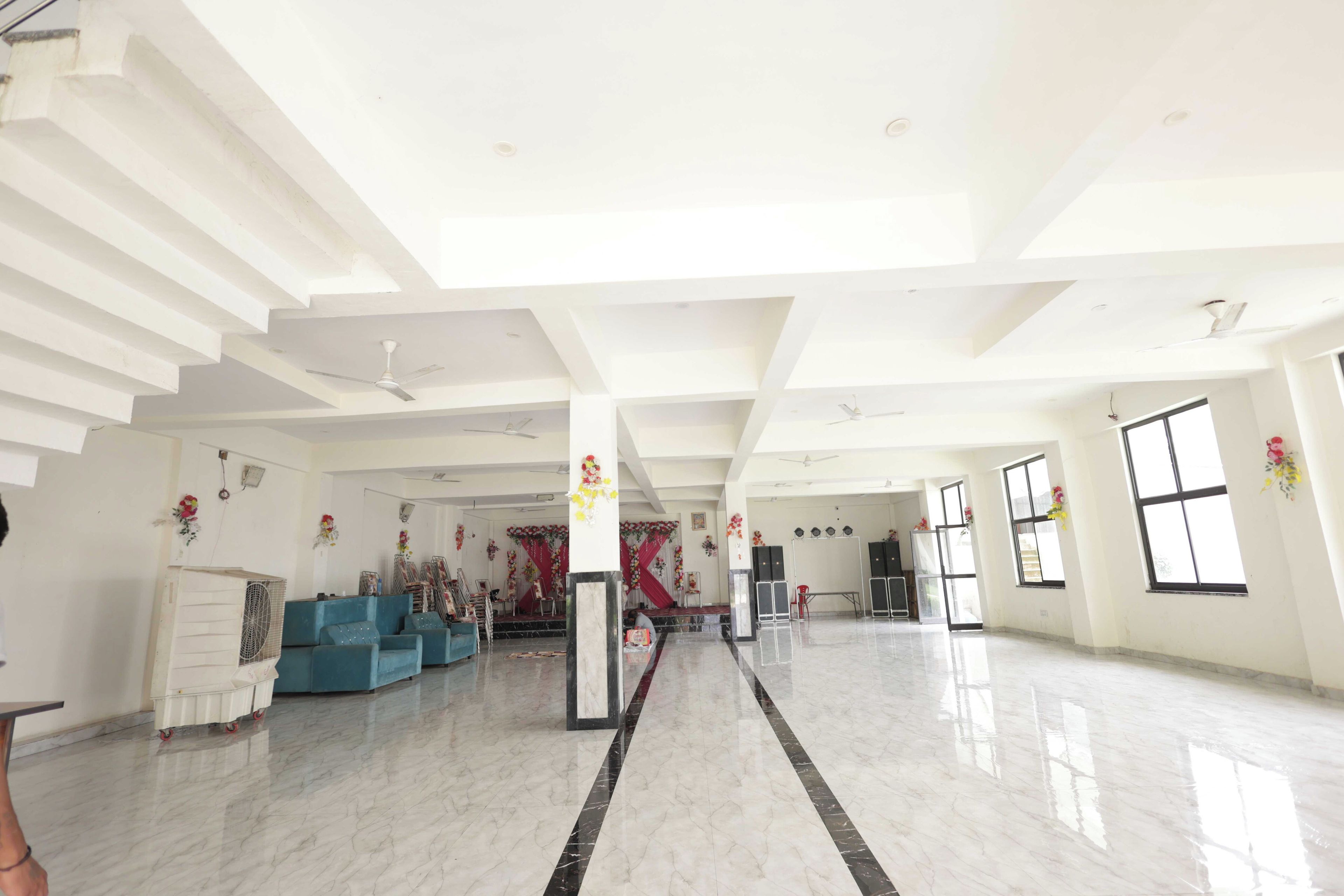 A spacious hall with a high ceiling, marble flooring, and a stage area with floral decorations.
