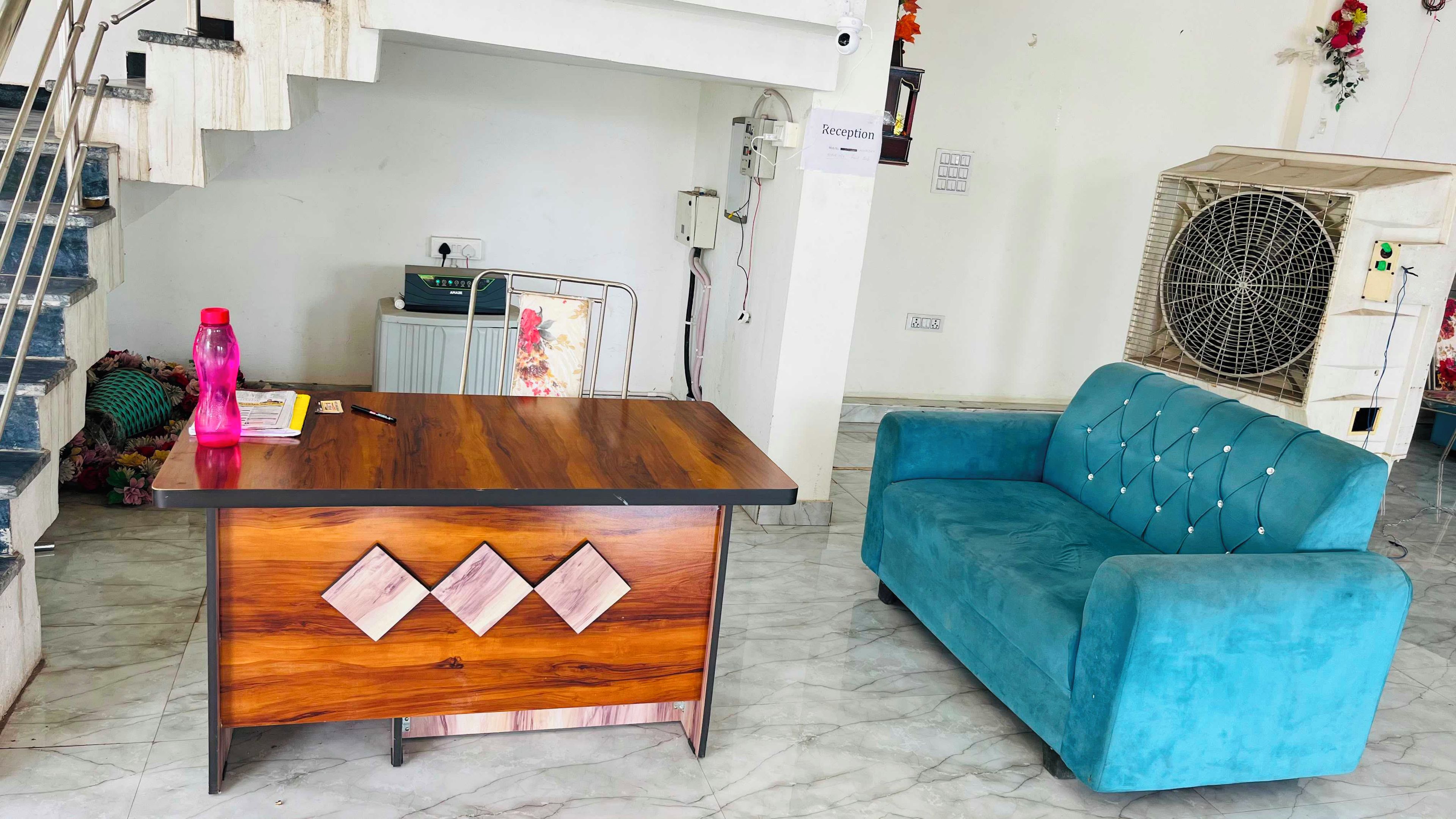 A reception desk with a wooden finish and a blue sofa in a room with a tiled floor.