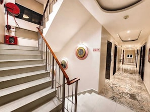 Ein Hotelinnenraum mit Treppe, einem Fluchtwegweiser und einem Gang zu einem Zimmer.