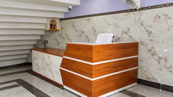 A reception desk with a marble wall and a ceiling fan.