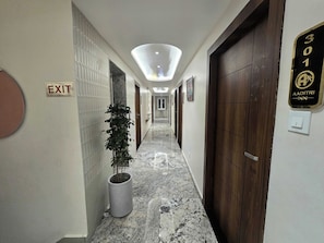 Ein Hotelgang mit einem Fluchtwegschild, einem Topf mit einer Pflanze, einem Marmorboden und einer Tür mit dem Schild Zimmer 301.
