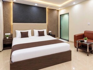 Ein modernes Hotelzimmer mit einem großen Bett, Nachttischen, einer Sitzecke und einer Glastür zum Badezimmer.