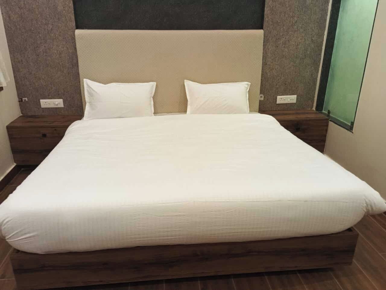 A large bed with a white mattress and two pillows, flanked by wooden nightstands with a modern design.
