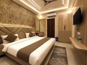 Ein Hotelzimmer mit einem großen Bett, einem Flachbildfernseher, einem Kleiderschrank und einem Deckenventilator.