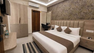 A modern hotel room with a large bed, a flat-screen TV, a wardrobe, and a bathroom with a shower.