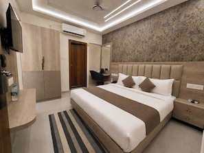 Ein modernes Hotelzimmer mit einem großen Bett, einem Flachbildfernseher, einem Kleiderschrank und einem Badezimmer mit Dusche.