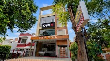 A hotel with a modern facade, a prominent signboard, and a gated entrance.