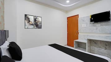 A hotel room with a bed, a TV mounted on the wall, and a door.