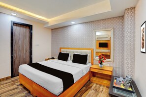 Een hotelkamer met een groot bed, nachtkastjes, een spiegel en een tafeltje met een vaas en kopjes.