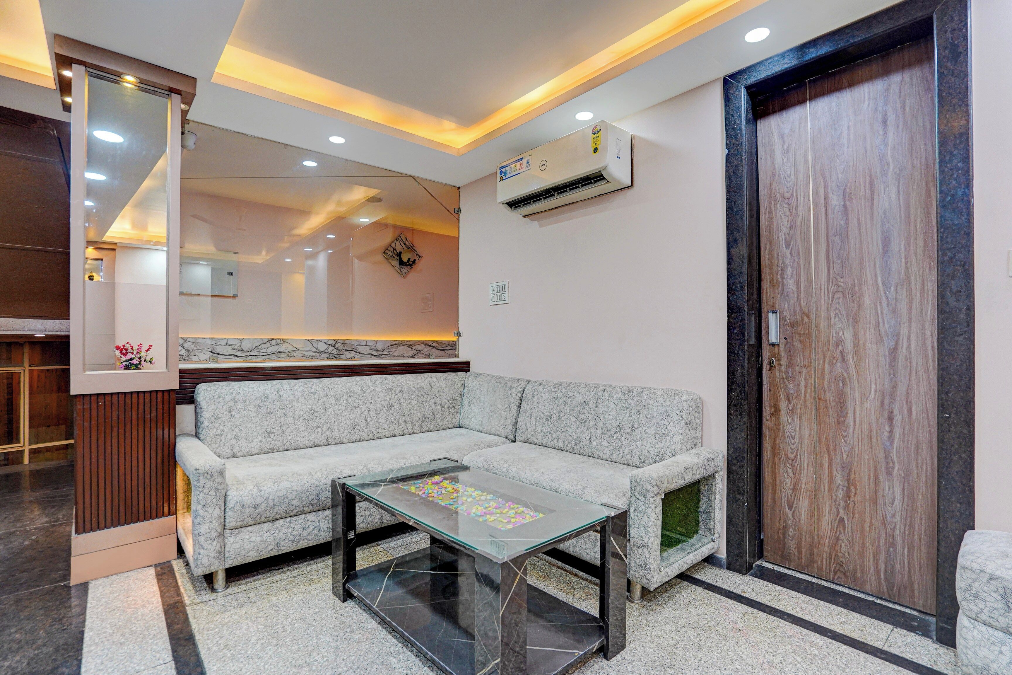 A modern living room with a sofa, a glass coffee table, and a wooden door.