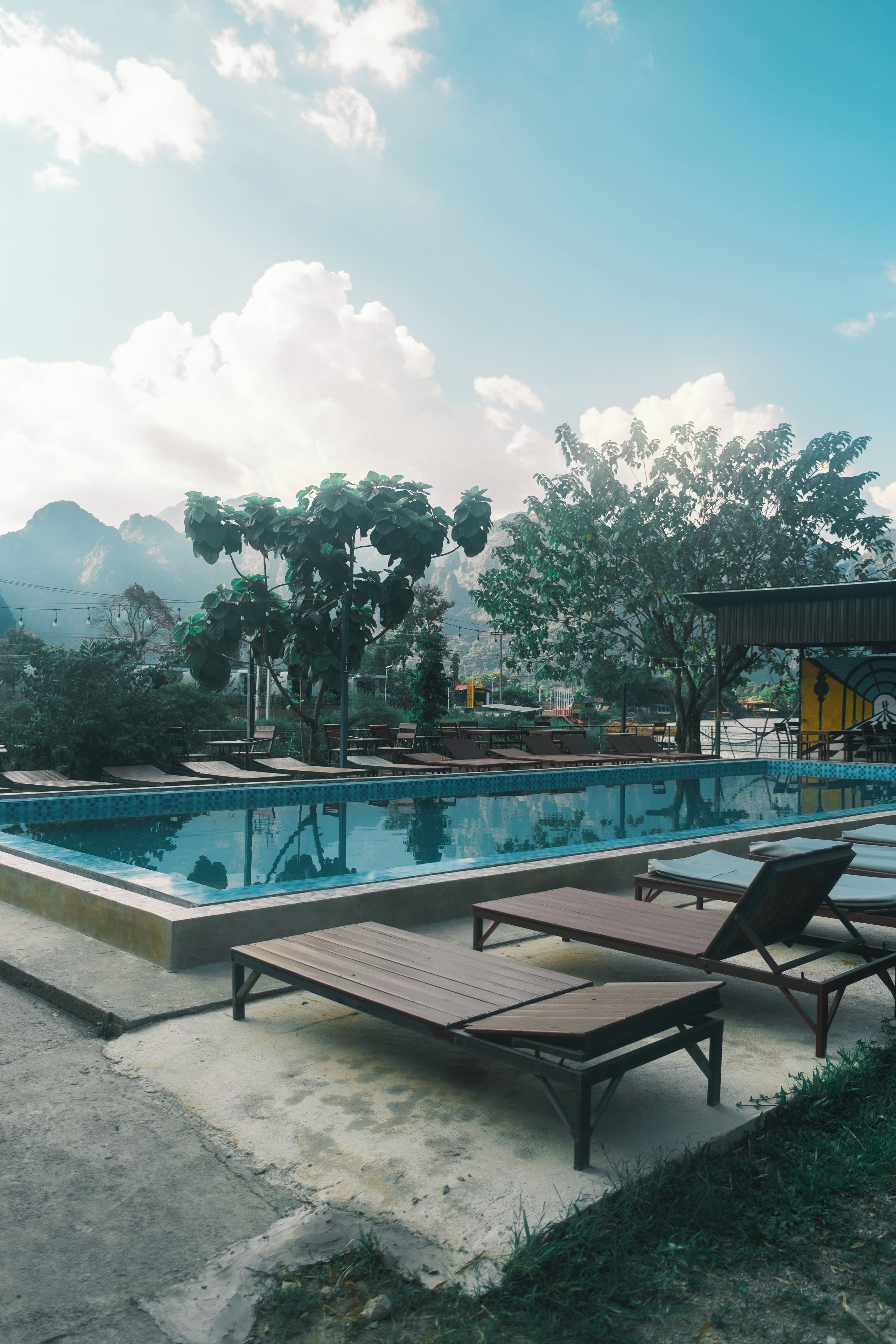 A swimming pool with lounge chairs and a view of mountains in the background.