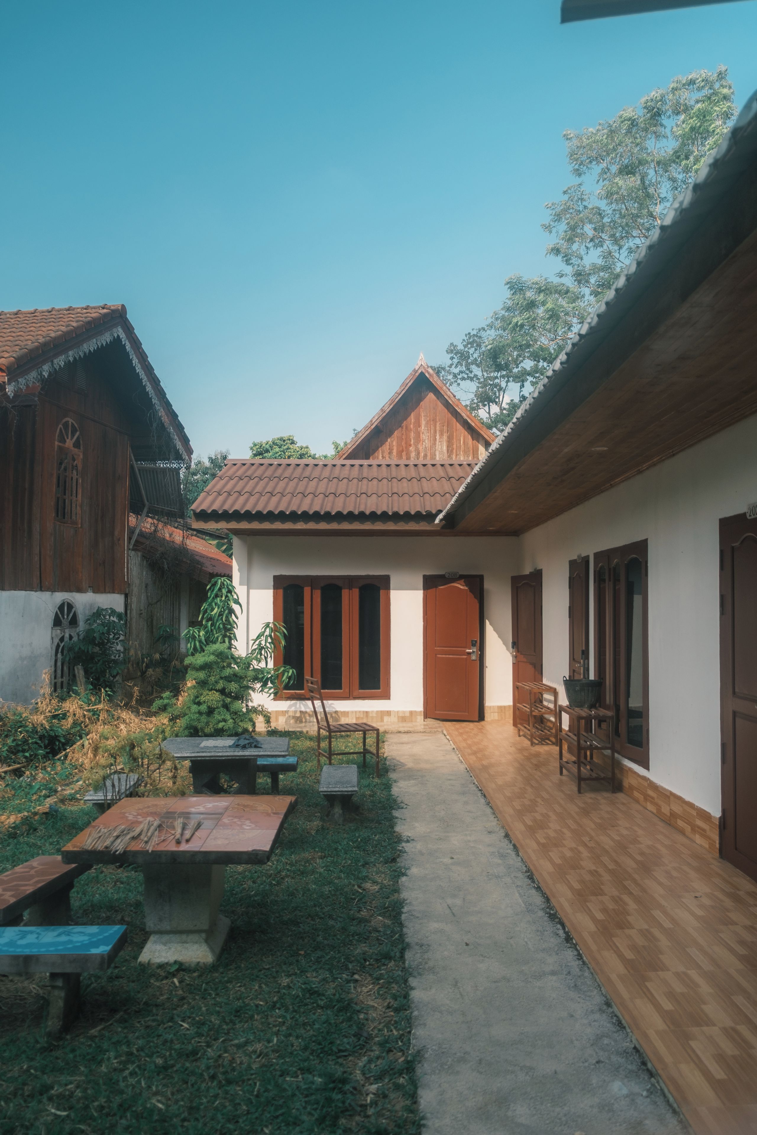 A courtyard with a wooden bench, a table, and a door leading to a room.