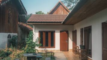 A courtyard with a wooden bench, a table, and a door leading to a room.