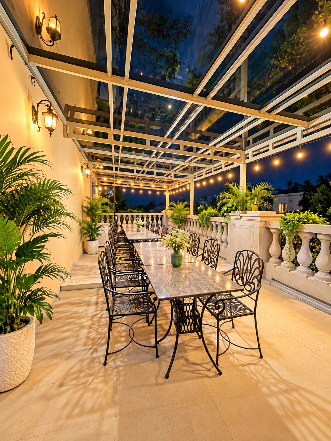 An outdoor patio with a long dining table, chairs, and potted plants.