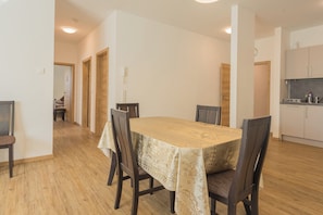 A dining area with a table set for four, wooden chairs, and a kitchen area with cabinets and a countertop.