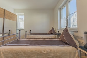 A dormitory room with two beds, a window, and a view of the outside.