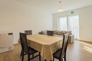 A dining area with a table, chairs, a washing machine, and a window with curtains.