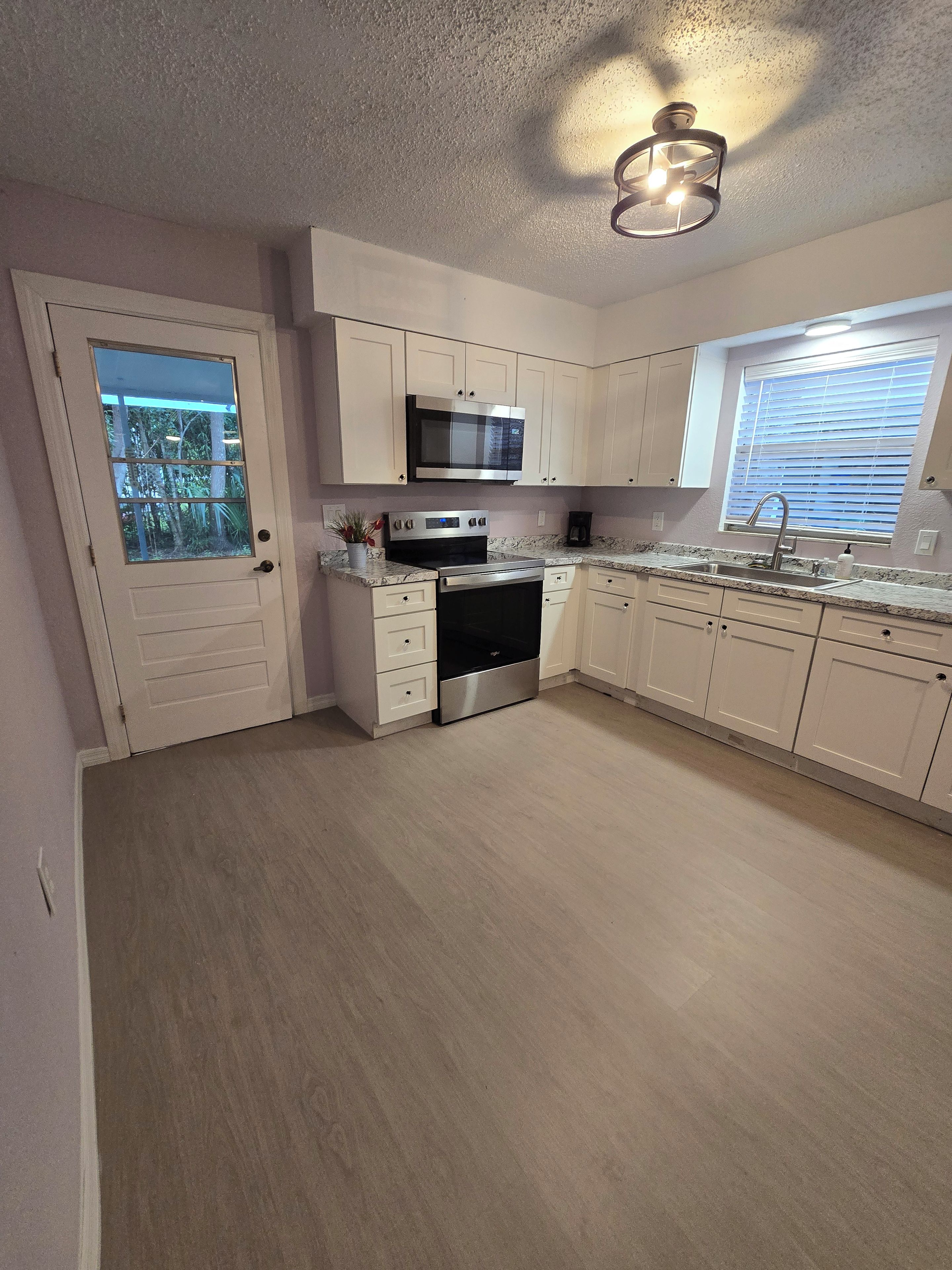 A kitchen with a microwave, stove, and sink.