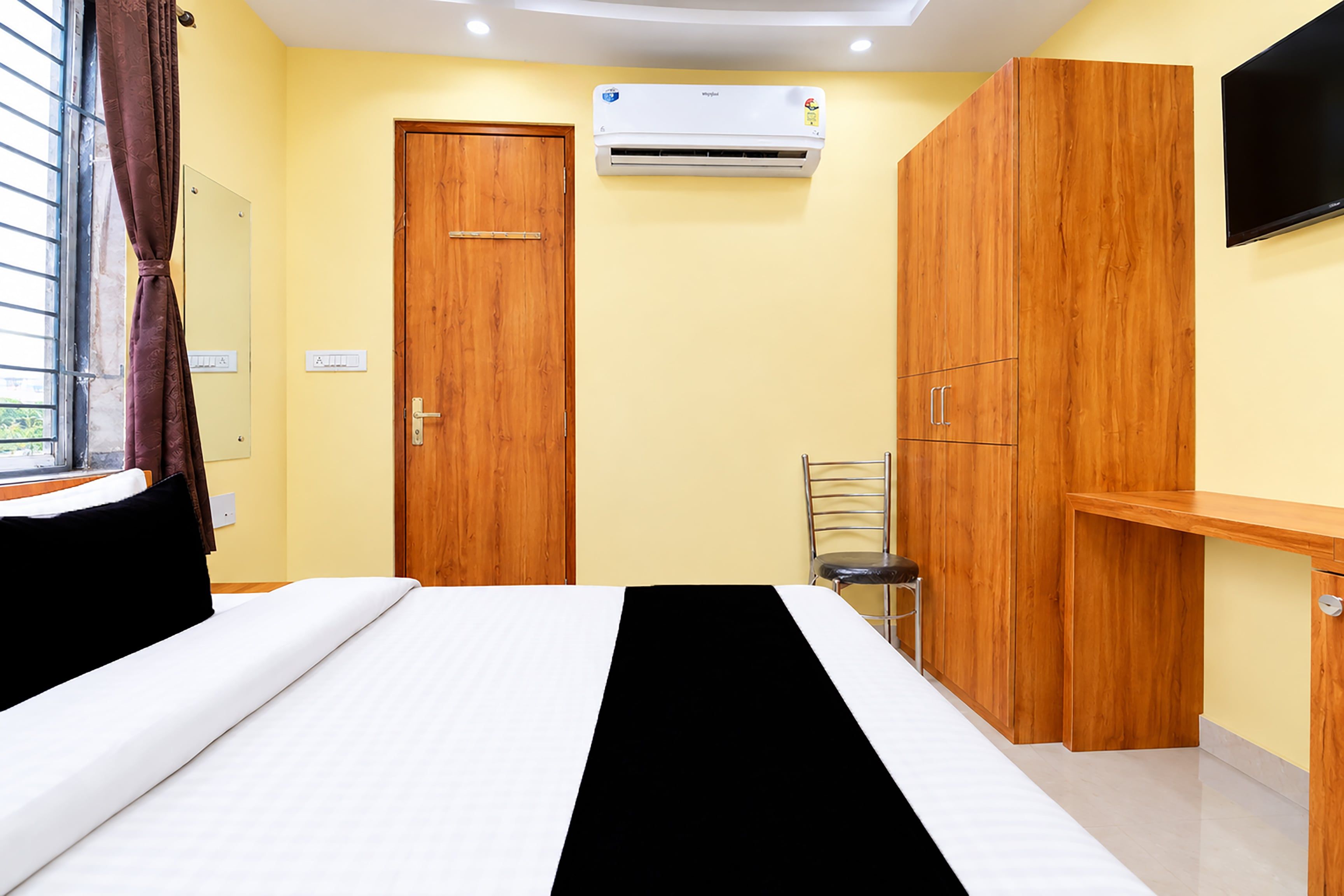Un dormitorio con cama, armario, silla y equipo de aire acondicionado.