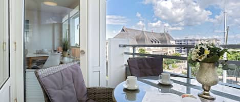 A balcony with wicker furniture, a table with a newspaper, and a vase with flowers.