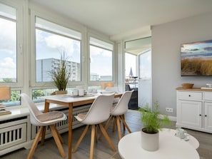 A modern kitchen with a dining area, large windows, and a view of the city. - Holiday Apartment With 2 Bedrooms (Sylt)