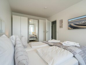 A modern bedroom with a bed, a wardrobe, and a painting on the wall. - Holiday Apartment With 2 Bedrooms (Sylt)