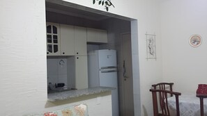 A compact kitchen with a refrigerator, cabinets, and a small countertop. - New Listing (Guarujá)