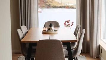 Un comedor con una mesa, sillas, una lámpara colgante y vistas al exterior.