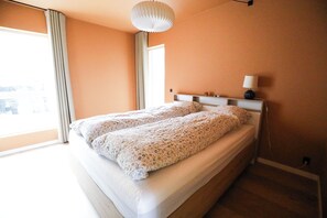 A bedroom with a bed, a bedside table with a lamp, and a window with curtains. - UK 39, 1. TV (Argir)
