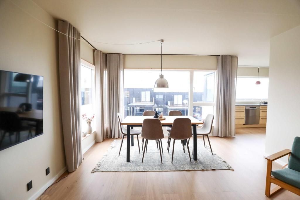 Un comedor moderno con una mesa grande, sillas y vistas a través del ventanal.