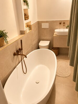 A modern bathroom with a freestanding bathtub, a toilet, and a sink. - New Listing (Paris)